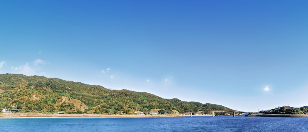 施設周辺の海と緑の丘陵地帯。晴天の瀬戸内海沿いの景観。